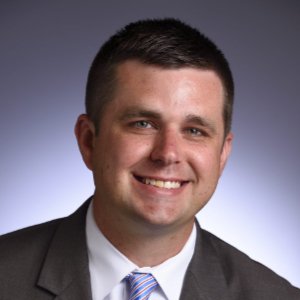 Drew Alexander smiling in a grey suit