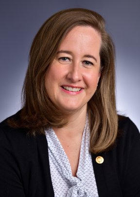 Sharon Bradley smiling in a white blouse and black blazer