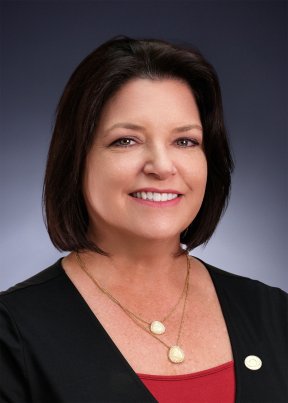 Christina Ott smiling in red shirt and black blazer